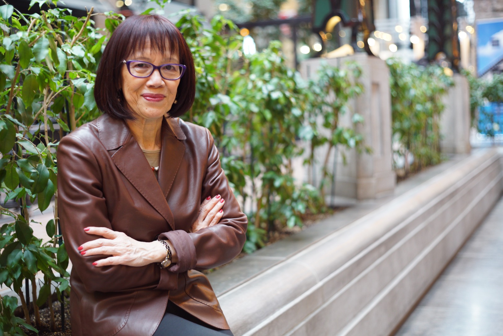 Simone Hoa Aubrey in a brown leather jacket with arms crossed